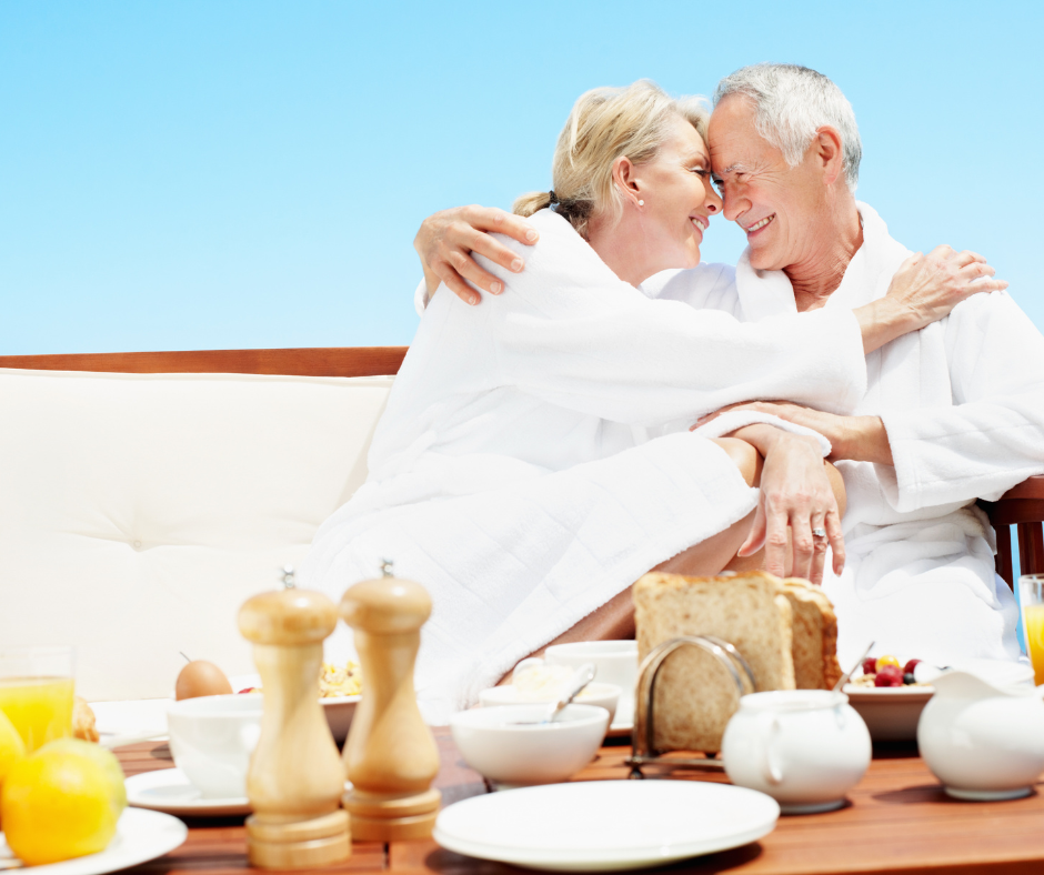 A couple in white robes holding each other with breakfast in front of them.