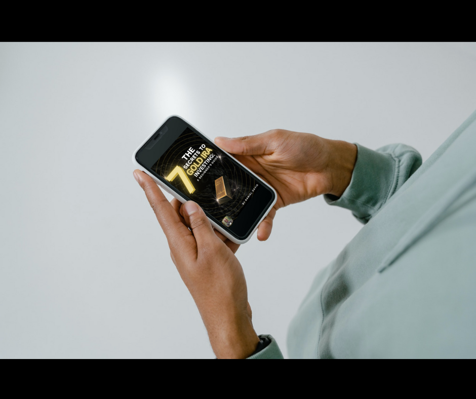 Male holding his mobile looking at the book. The-7-secrets-to-gold-ira-investing-a-beginners-guide.