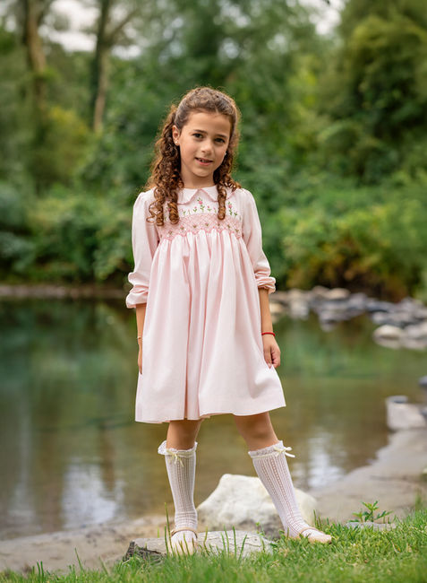 Little girl standing near water outdoors in soft natural light