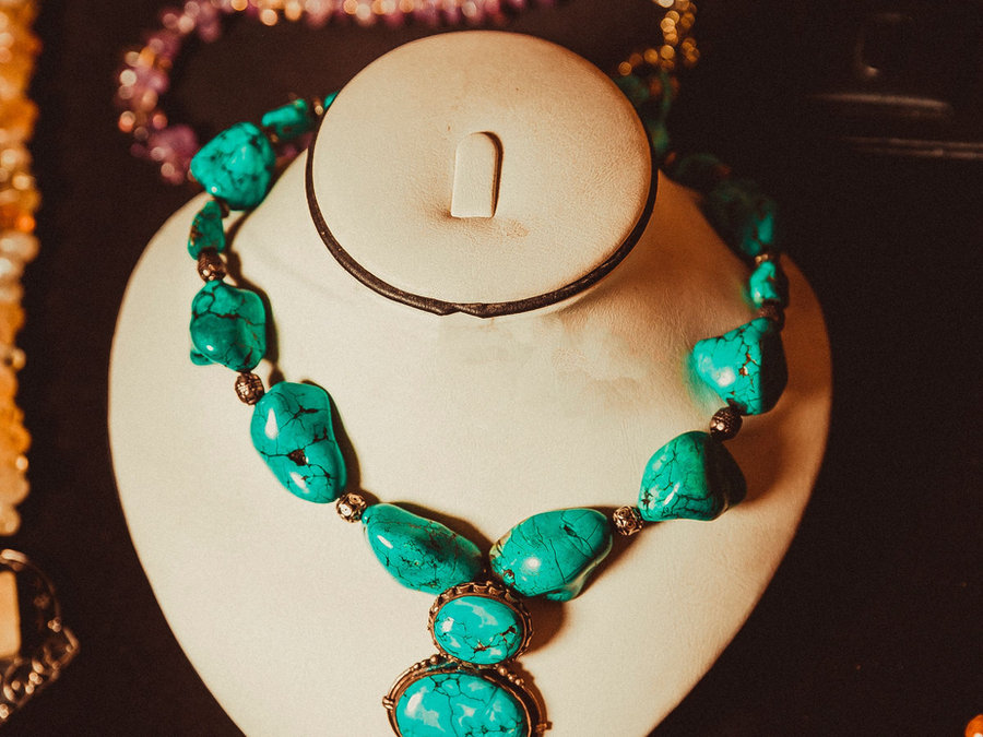 A turquoise necklace displayed on a jewelry bust