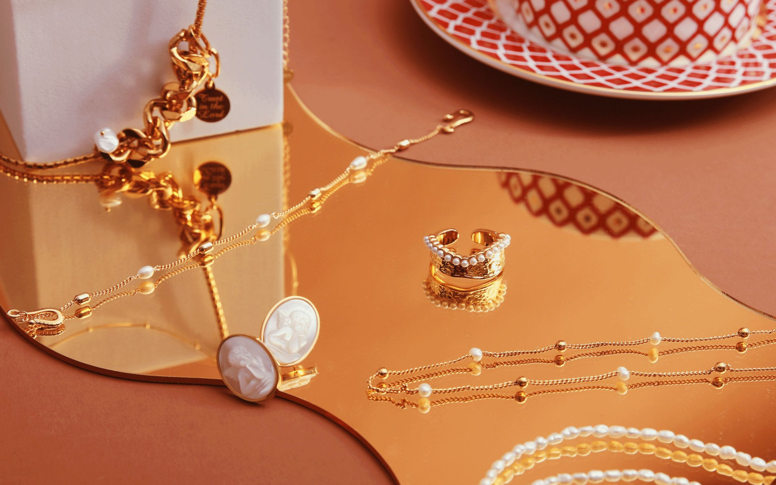 Gold jewelry and pearls on a warm table