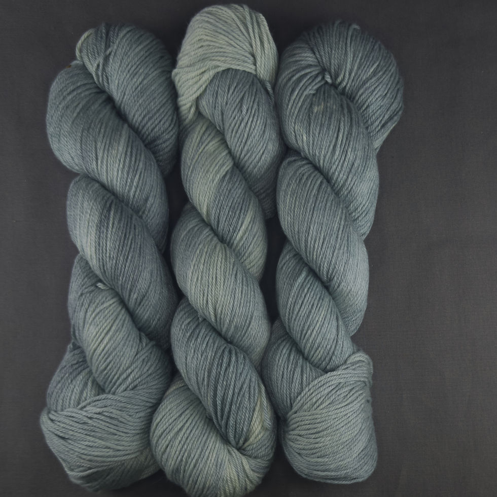 Hand-dyed yarn skeins in cool river blue, grey-green, misty sage, and pale stone shades.