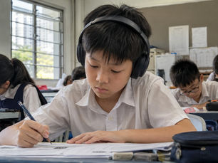 A Primary 6 boy wearing headphones during listening practice in class