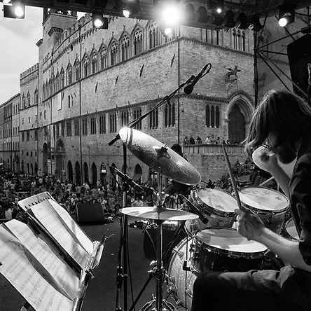 Riccardo, drum teacher at Inspired Playing, performing on stage during a concert, passionately playing a drum set.