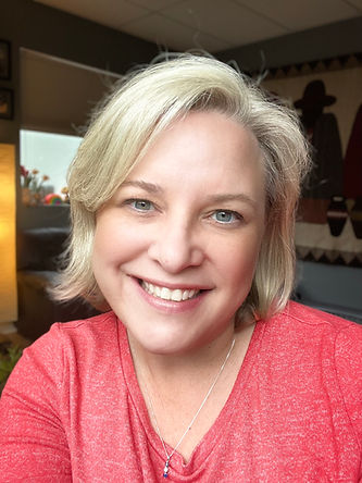 Cary Hamilton smiling looking into the camera with chin length blonde hair and a red top.