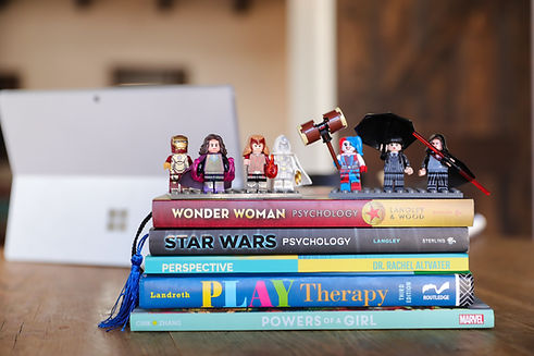 Pile of pop culture psychology books stacked with several pop culture lego figures standing on top.