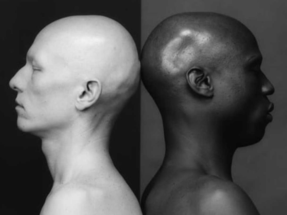 Side-by-side black-and-white portraits of two bald people in profile, one pale and one dark, facing opposite directions.