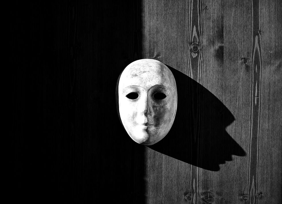 White theatrical mask on a dark wooden wall, casting a long shadow in stark black-and-white light.