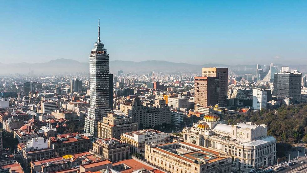 Clear city skyline with Torre Latinoamericana rising above buildings and the domed Palacio de Bellas Artes under a blue sky.