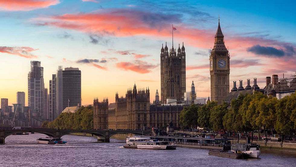 London skyline at sunset with Big Ben and the Houses of Parliament beside the Thames, boats below and pink clouds.
