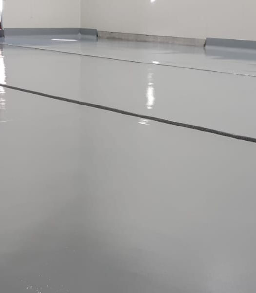 Professional Epoxy Flooring Installation with a high-gloss grey finish and integrated floor drainage for an industrial facility.