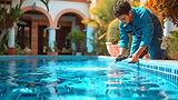 Reliable pool professional in uniform performing routine weekly skimming and maintenance for an Orlando pool.