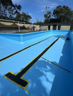 Expert application of black lane markings and "T" symbols over a fresh blue Custom Concrete Resurfacing pool finish, showcasing the precision of JC Flooring & Coatings.
