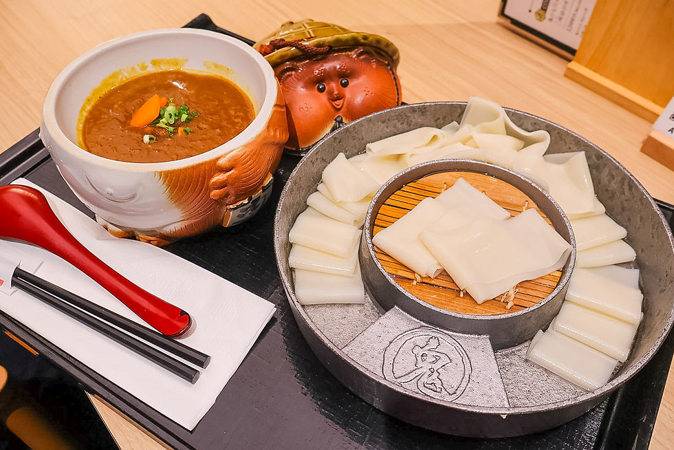 Japanese meal tray with curry in a smiling character bowl, sliced rice cakes on a pan, and chopsticks with a red spoon on a napkin