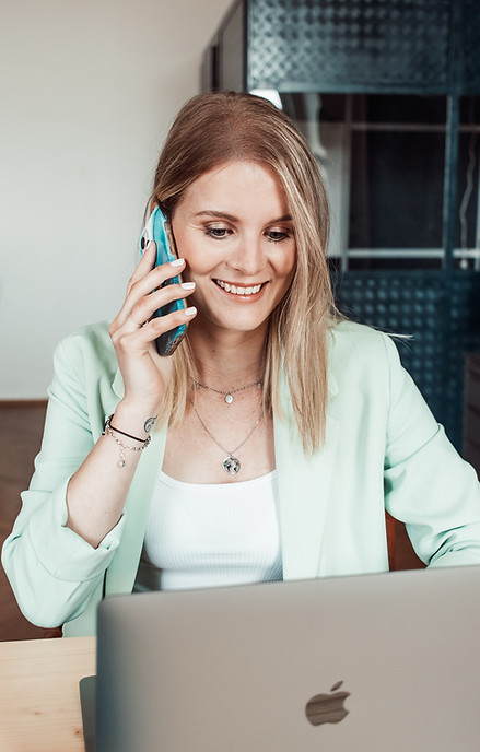 Bettina von Tinamarketing im Gespräch am Telefon vor dem Laptop, Ansprechpartnerin für Social Media Marketing für Unternehmen im deutschsprachigen Raum
