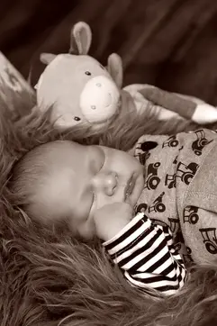 Baby schläft tief in gestreiftem Shirt.