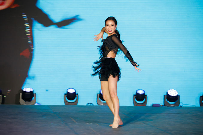 A 2024 HI-TEEN USA® CONTESTANT PERFORMING A DANCE ON STAGE IN A BLACK DRESS FOR HER TALENT