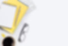 Copywriter's desktop with keyboard, yellow notepad, pen and eyeglasses\