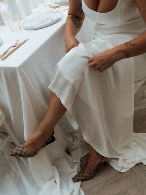 A bride adjusting her dress with her Gucci heels peeping out