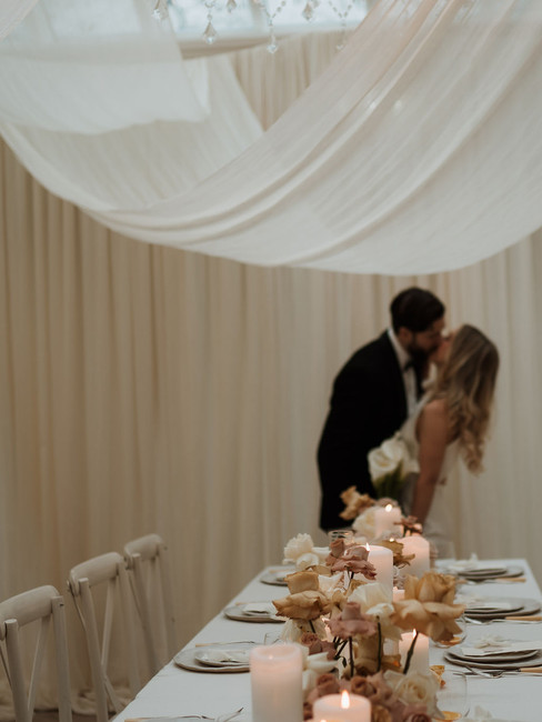 bride and groom kissing by their wedding breakfast table