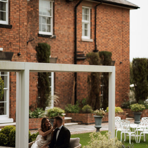 bride and groom sitting underneath a pergola enjoying their wedding