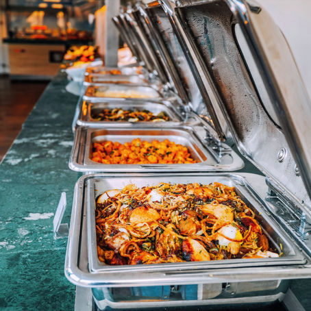 „Afrikanische Gerichte in Warmhaltebehältern auf einer Buffet-Theke“