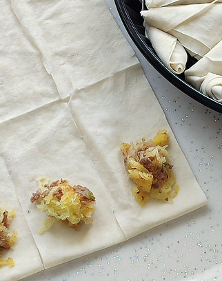 "Hand-rolled samousas being prepared with pastry sheets and spicy filling"