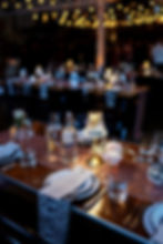 a wedding tablescape with a wood banquet table, pinky sparkly runner, leopard print napkins, plates, glassware, menus, bud cases with flowers and lamps