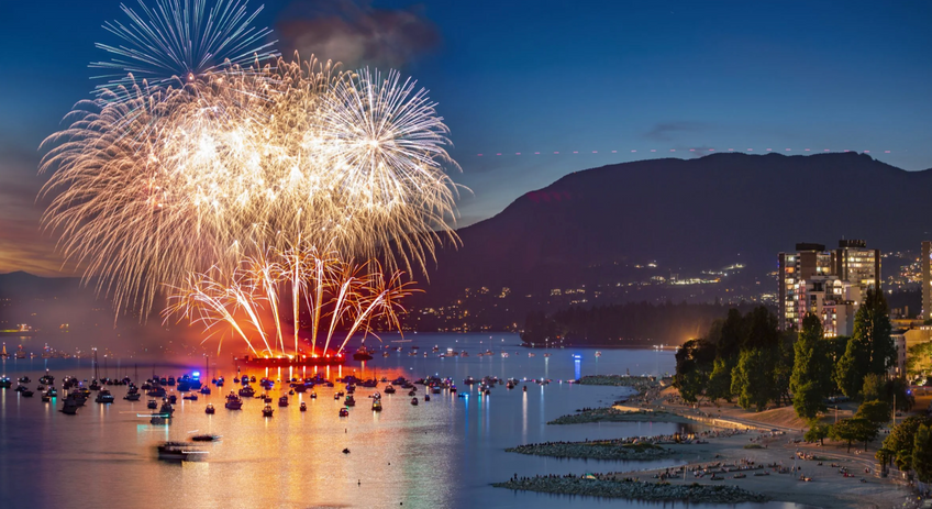 White fireworks exploding over English Bay skyline in Vancouver, seen from a boat cruise