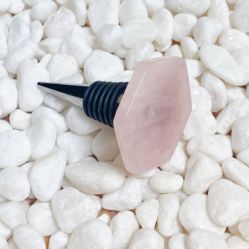 Thumbnail: A rose quartz bottle stopper with a polished, faceted top rests on smooth white pebbles.