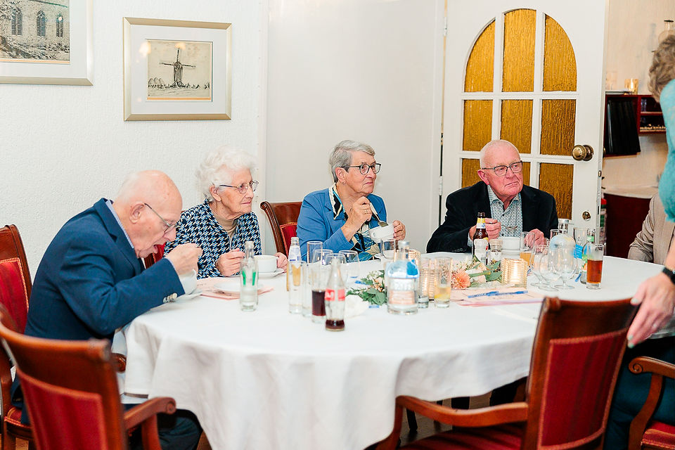 Oudere gasten genieten van diner aan ronde tafel met kaarslicht en stijlvol decor