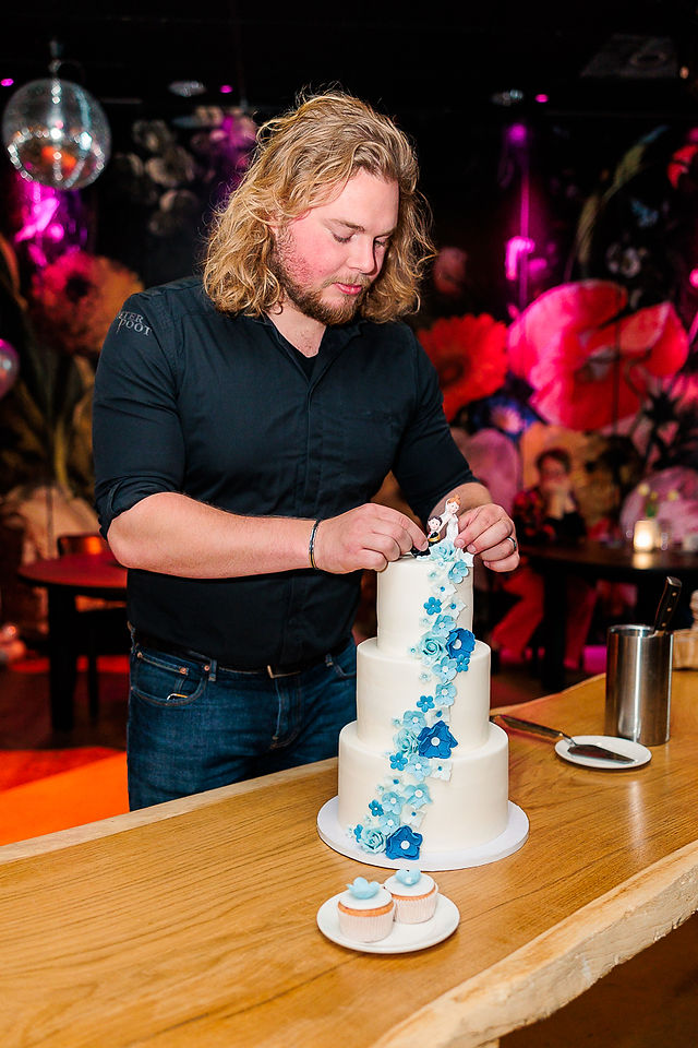 Pieter poot medewerker zet de taart topper op de bruidstaart goed