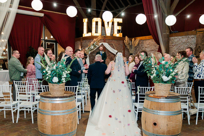 Bruid loopt de ceremonie binnen bij Hermans Dijkstra in Midwolda ā kleurrijke trouwjurk en warme momenten vastgelegd door Renke Fotografie.
