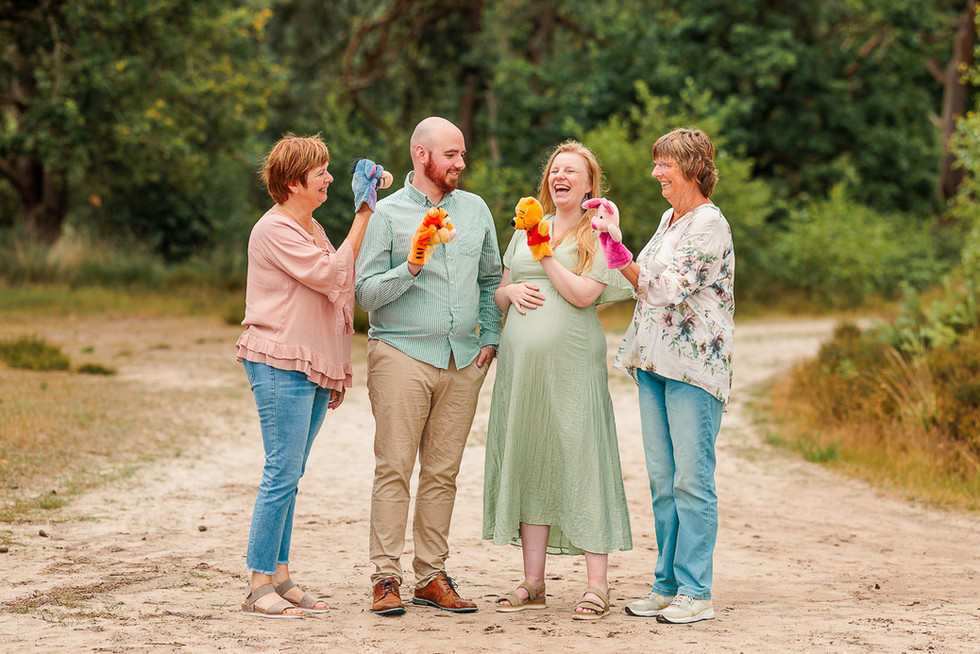 gezin staat te lachen met handpoppen in hun hand