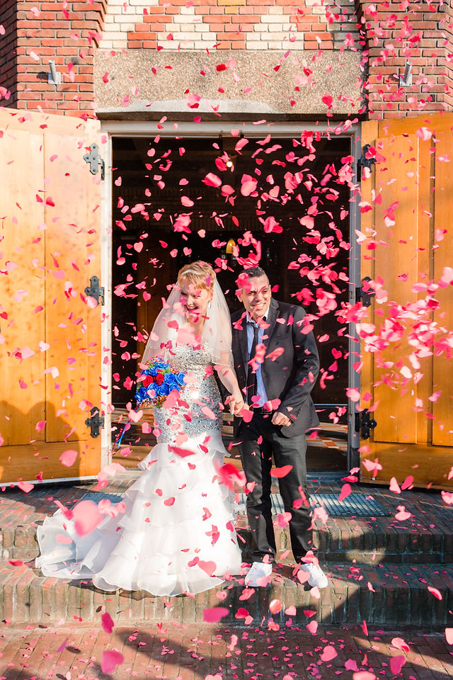 Bruidspaar wordt na de huwelijksceremonie onthaalt door gasten en confetti
