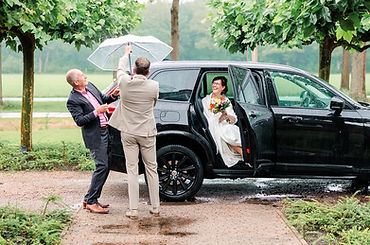 Regenachtige trouwdag in Drenthe, bruidegom klapt de paraplu uit voor de bruid