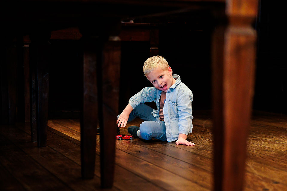 jongen speelt onder de tafel tijdens het feest van zijn opa en oma