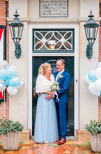 Echtpaar dat hun jubileum viert bij een feestelijk versierde entree, met warme begroetingen en een ontspannen sfeer.