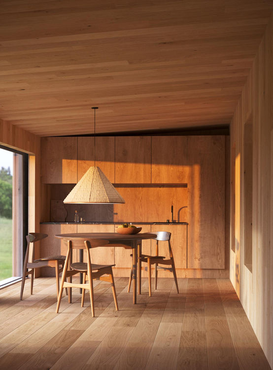 Scandinavian-style kitchen interior with natural wood cabinetry, matching floor and ceiling, round dining table, and large window with garden view.