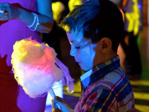 Child holding colourful candy floss under bright party lights at an event creating a fun and interactive dessert experience for guests in the UK