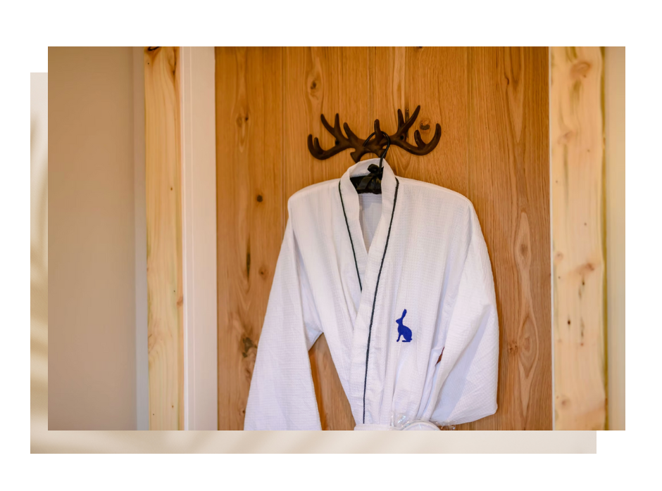 White bathrobe with bunny logo hanging on wooden wall in room