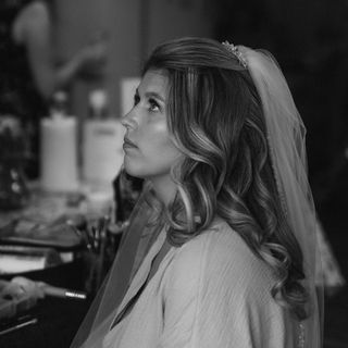 Bride with long, flowing waves, softly brushed out for a natural, romantic finish, paired with a delicate ivory veil.