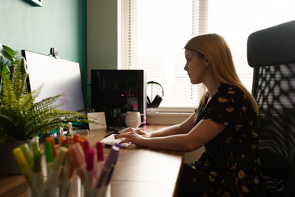 A calligraphy at her desk typing something. There are brush pens and a plant on her desk.