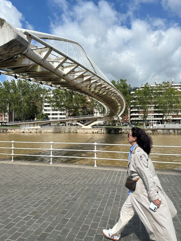 Eine junge hell gekleidete Frau schreitet an der weißen Zubizuri-Brücke vorbei