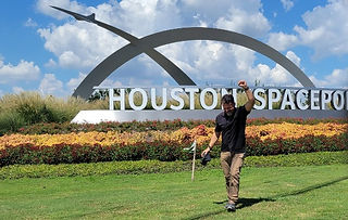 a photographer raises his fist in victory near the Houston Spaceport sign