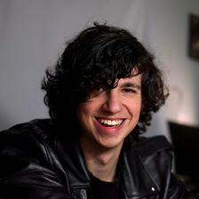 Jeremy Haney Smiling in a White Room, Wearing Black Leather Jacket