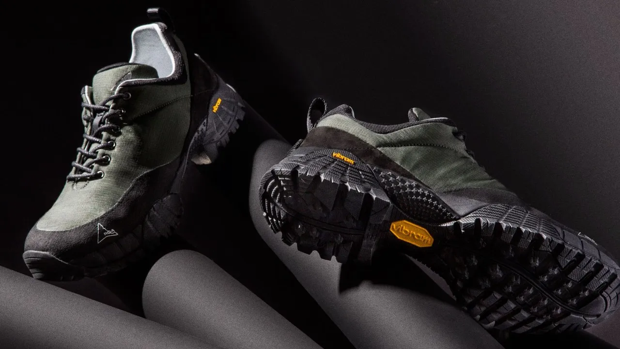 Dark rugged shoes, one showing sole with yellow Vibram logo