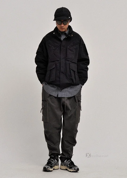 Person standing in black jacket, cargo pants, and sneakers.