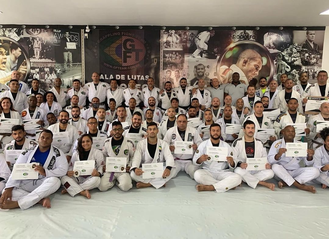 Around fifty GFTeam students seated on the mats of the Méier headquarters in front of the team mural