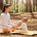 vue-laterale-jeune-mere-sportive-heureuse-assise-karemat-foret-son-bebe.jpg